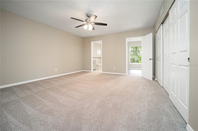 unfurnished bedroom with light carpet, connected bathroom, and ceiling fan