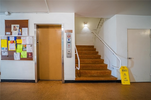 staircase featuring elevator and dark carpet