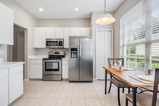 kitchen with white cabinetry, light tile patterned floors, decorative light fixtures, and appliances with stainless steel finishes