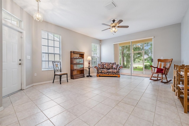 living area featuring light tile patterned flooring and ceiling fan with notable chandelier