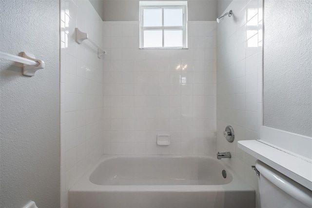 bathroom featuring toilet and tiled shower / bath