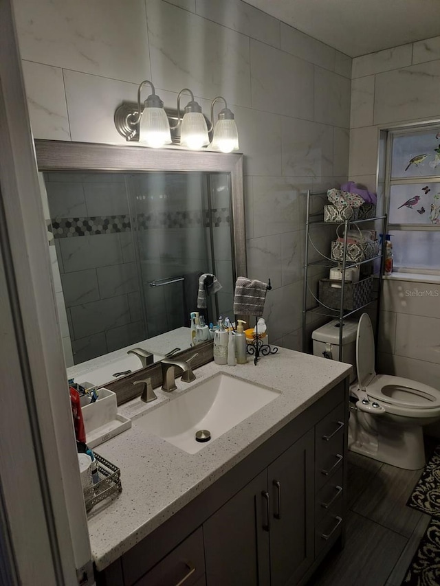 bathroom featuring vanity, toilet, and tile walls