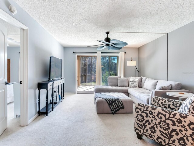 carpeted living room with ceiling fan and a textured ceiling