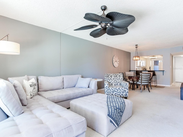 living room with ceiling fan, carpet flooring, and a textured ceiling