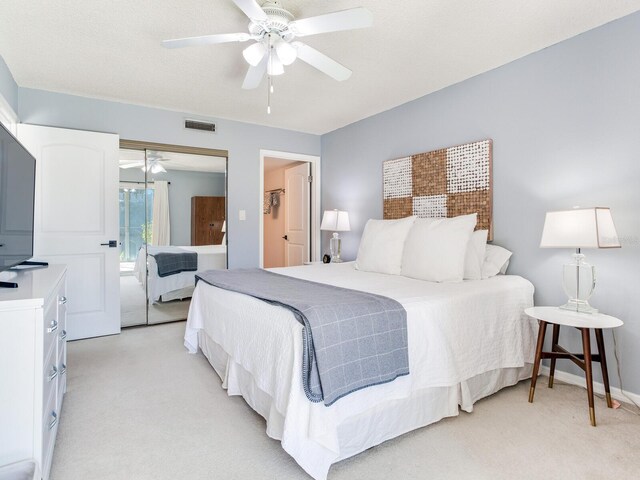 bedroom with a closet, ceiling fan, light carpet, and a textured ceiling