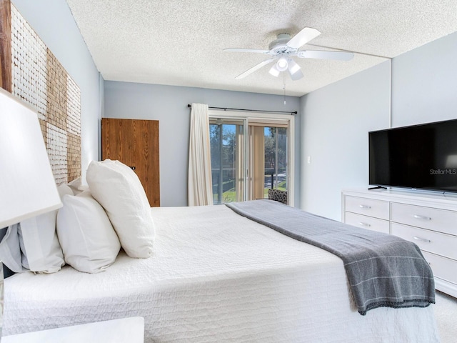 bedroom featuring ceiling fan, access to exterior, and a textured ceiling