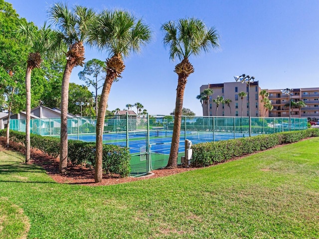 view of tennis court featuring a yard and fence