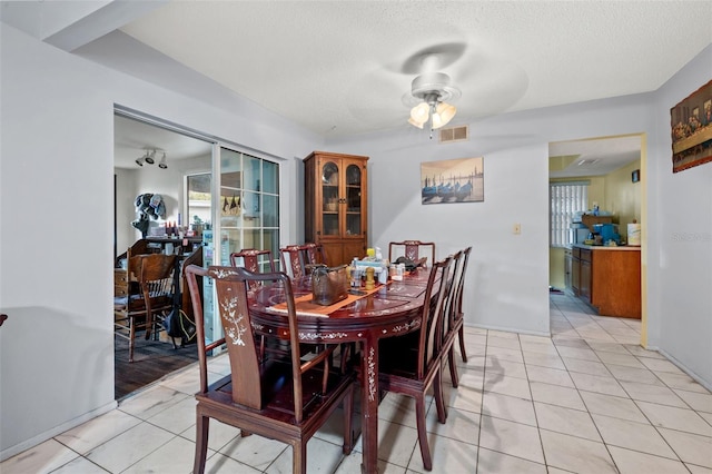 tiled dining room with ceiling fan and a textured ceiling