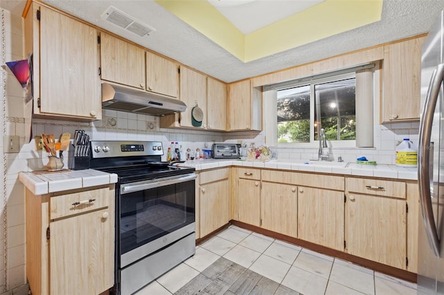 kitchen featuring light tile flooring, appliances with stainless steel finishes, sink, tile countertops, and tasteful backsplash