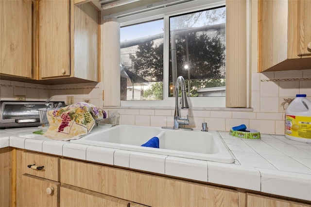 kitchen with tasteful backsplash, tile counters, and sink