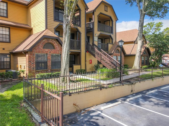 view of front facade with a balcony, central AC unit, and a front lawn