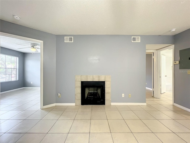 unfurnished living room featuring a textured ceiling, a fireplace, ceiling fan, and light tile floors