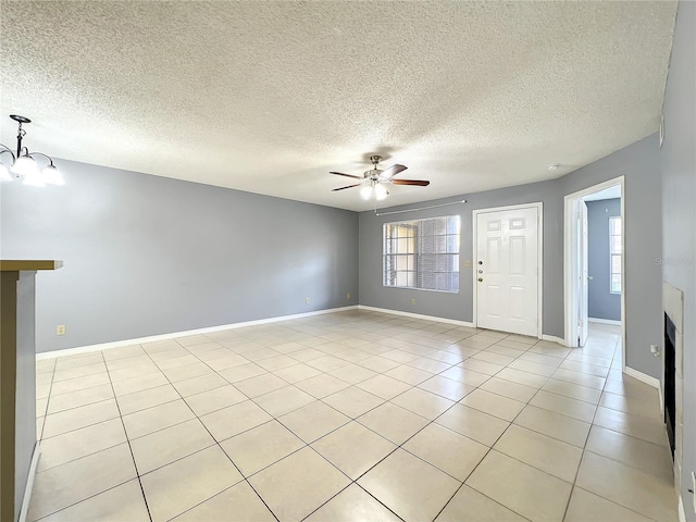 unfurnished room featuring light tile flooring, a textured ceiling, and ceiling fan with notable chandelier