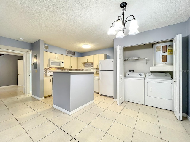 kitchen featuring a chandelier, light tile floors, white appliances, and washing machine and clothes dryer