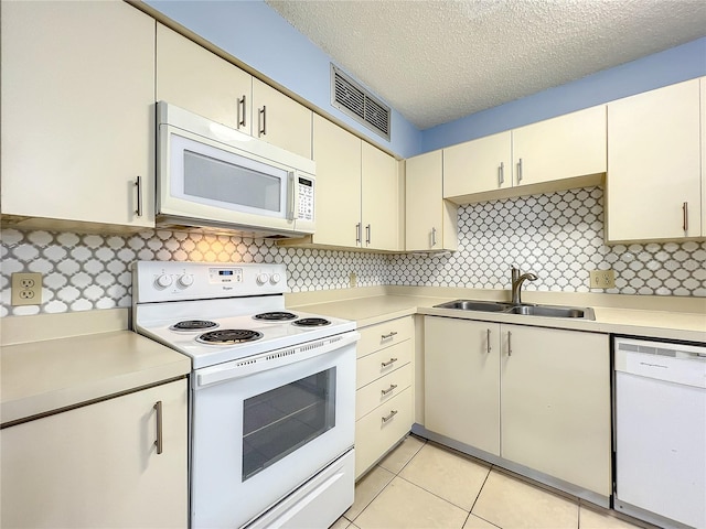 kitchen featuring light tile flooring, cream cabinetry, tasteful backsplash, white appliances, and sink