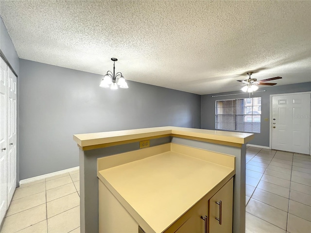 kitchen with light tile floors, hanging light fixtures, a textured ceiling, and ceiling fan with notable chandelier