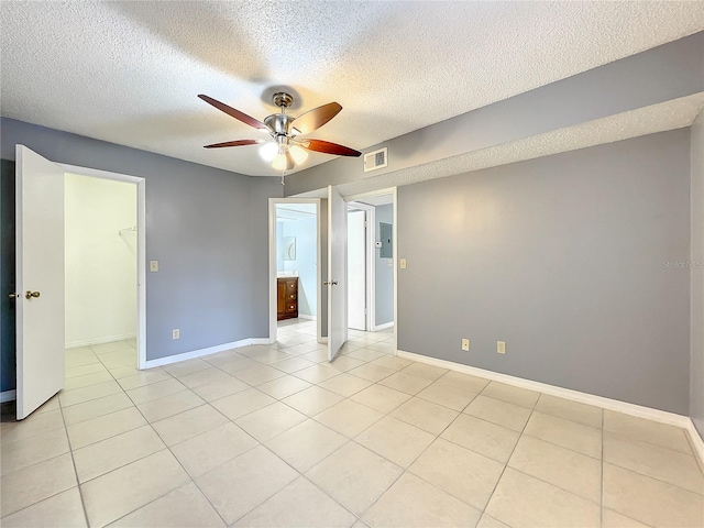 empty room featuring light tile floors, a textured ceiling, and ceiling fan