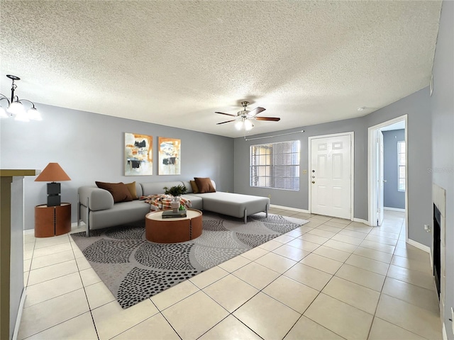 tiled living room with a textured ceiling and ceiling fan with notable chandelier