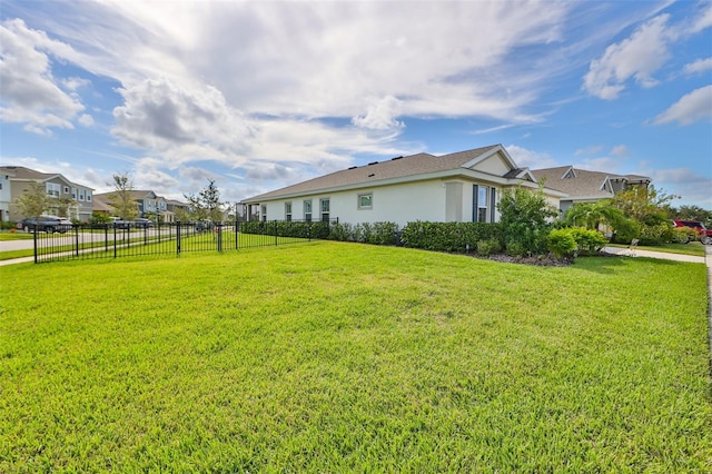 view of property exterior featuring stucco siding, a yard, and fence