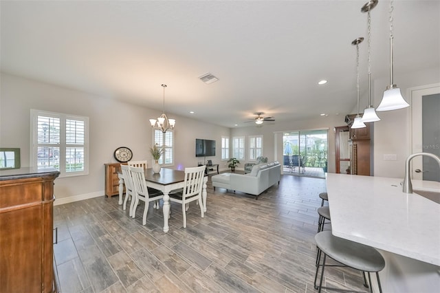 dining room with hardwood / wood-style flooring, ceiling fan with notable chandelier, and sink