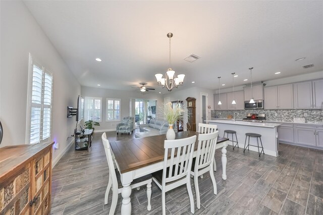 dining area with ceiling fan with notable chandelier, dark hardwood / wood-style flooring, and sink