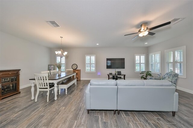 living room with dark hardwood / wood-style floors, ceiling fan with notable chandelier, and a wealth of natural light