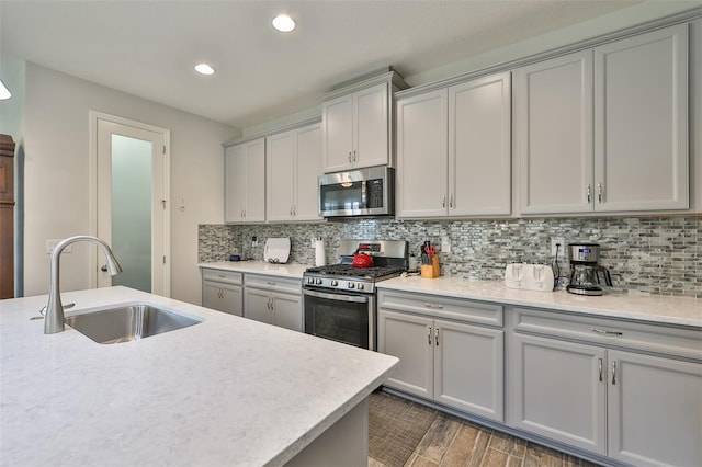 kitchen featuring appliances with stainless steel finishes, tasteful backsplash, sink, gray cabinets, and wood-type flooring