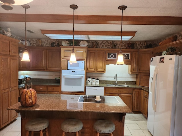 kitchen featuring pendant lighting, a kitchen breakfast bar, a kitchen island, white appliances, and sink