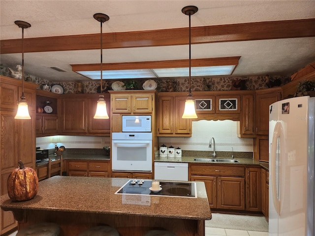 kitchen featuring decorative light fixtures, white appliances, a kitchen bar, sink, and tasteful backsplash