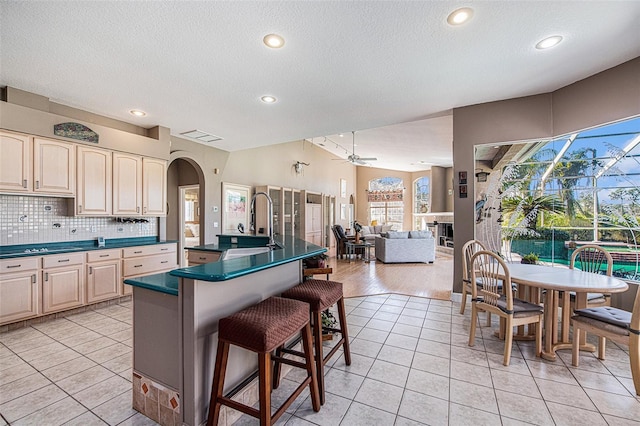 kitchen featuring a kitchen breakfast bar, tasteful backsplash, light tile patterned floors, and ceiling fan