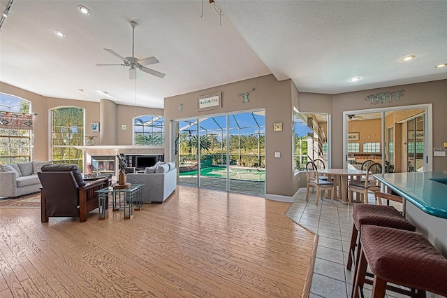 living room with ceiling fan, light hardwood / wood-style floors, and a textured ceiling