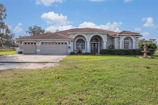 mediterranean / spanish-style home featuring a garage, a front yard, and french doors