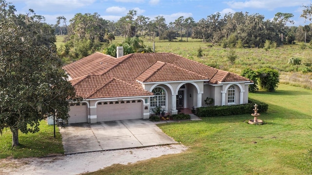 mediterranean / spanish home featuring a front yard and a garage