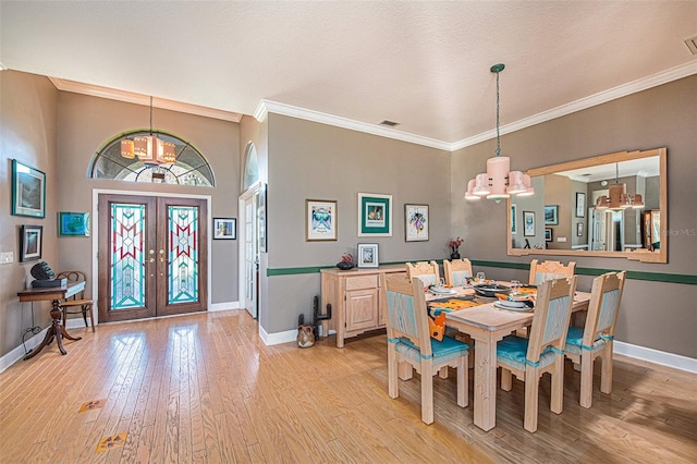 dining room with a chandelier, french doors, light wood-type flooring, and crown molding