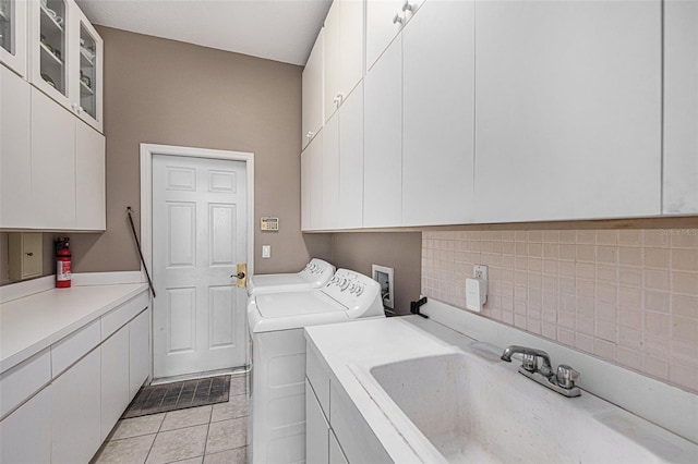 laundry area featuring cabinets, separate washer and dryer, sink, and light tile patterned floors