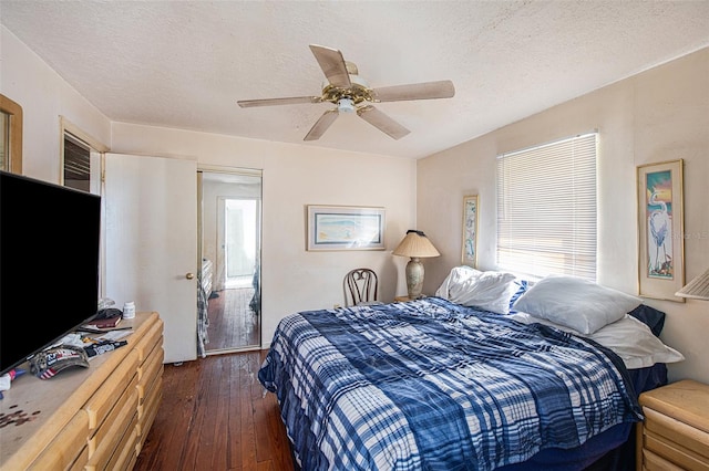 bedroom featuring dark hardwood / wood-style flooring, a textured ceiling, and ceiling fan