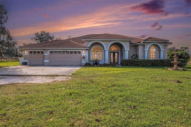 mediterranean / spanish-style home with french doors, a yard, and a garage