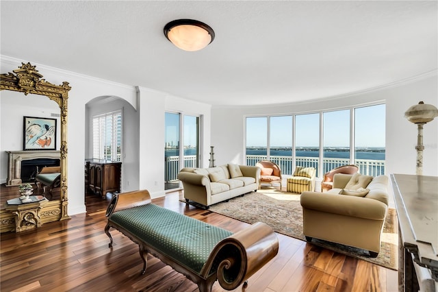 living room featuring hardwood / wood-style flooring, a water view, a wealth of natural light, and ornamental molding