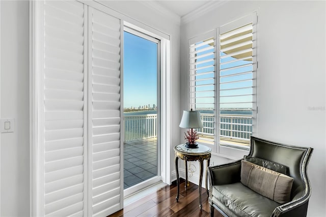 living area featuring ornamental molding, a water view, a healthy amount of sunlight, and dark hardwood / wood-style floors