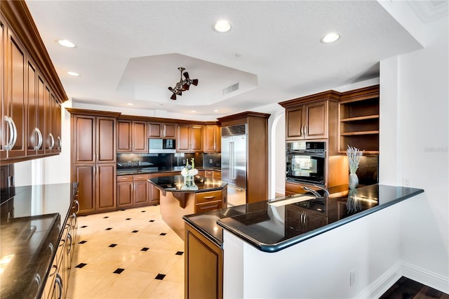 kitchen featuring stainless steel appliances, a raised ceiling, sink, a kitchen breakfast bar, and kitchen peninsula