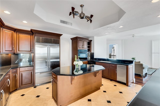 kitchen with stainless steel appliances, a center island, light tile patterned floors, tasteful backsplash, and ceiling fan