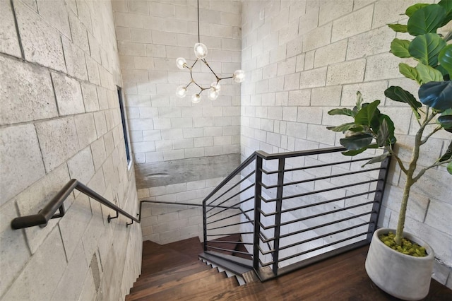 stairs featuring hardwood / wood-style floors and a notable chandelier