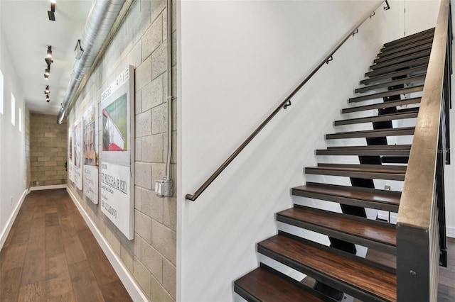 stairway featuring rail lighting and wood-type flooring