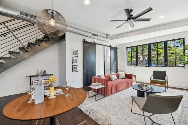 living room featuring hardwood / wood-style floors, a barn door, and ceiling fan