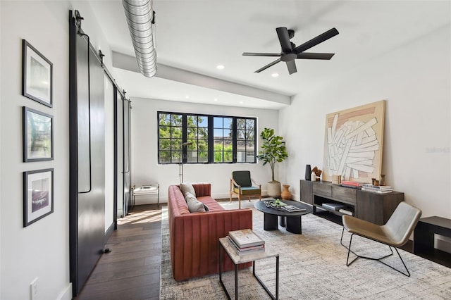 living room featuring dark wood-type flooring, a barn door, and ceiling fan