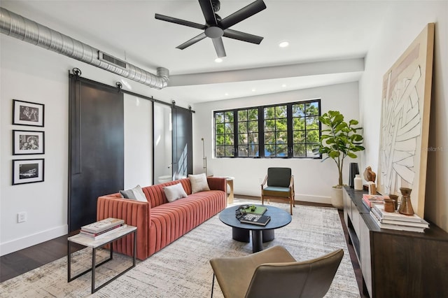 living room featuring a barn door, light hardwood / wood-style floors, and ceiling fan