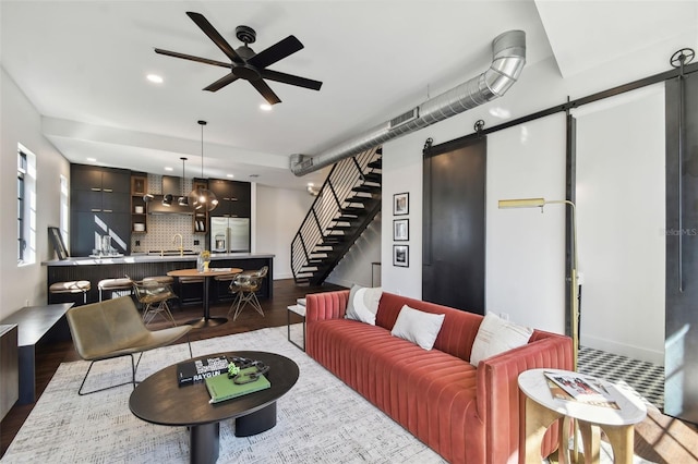 living room featuring a barn door, sink, ceiling fan, and dark hardwood / wood-style flooring