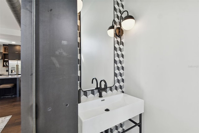 bathroom featuring hardwood / wood-style flooring, tasteful backsplash, and sink