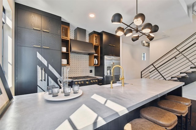 kitchen featuring sink, a kitchen bar, backsplash, stainless steel appliances, and decorative light fixtures