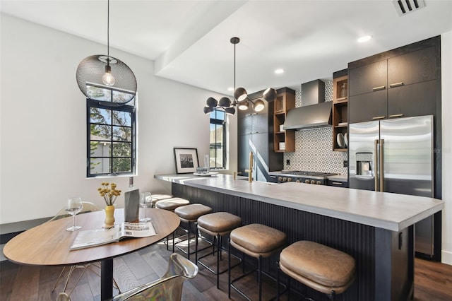 kitchen with wall chimney exhaust hood, a breakfast bar, pendant lighting, and dark hardwood / wood-style flooring